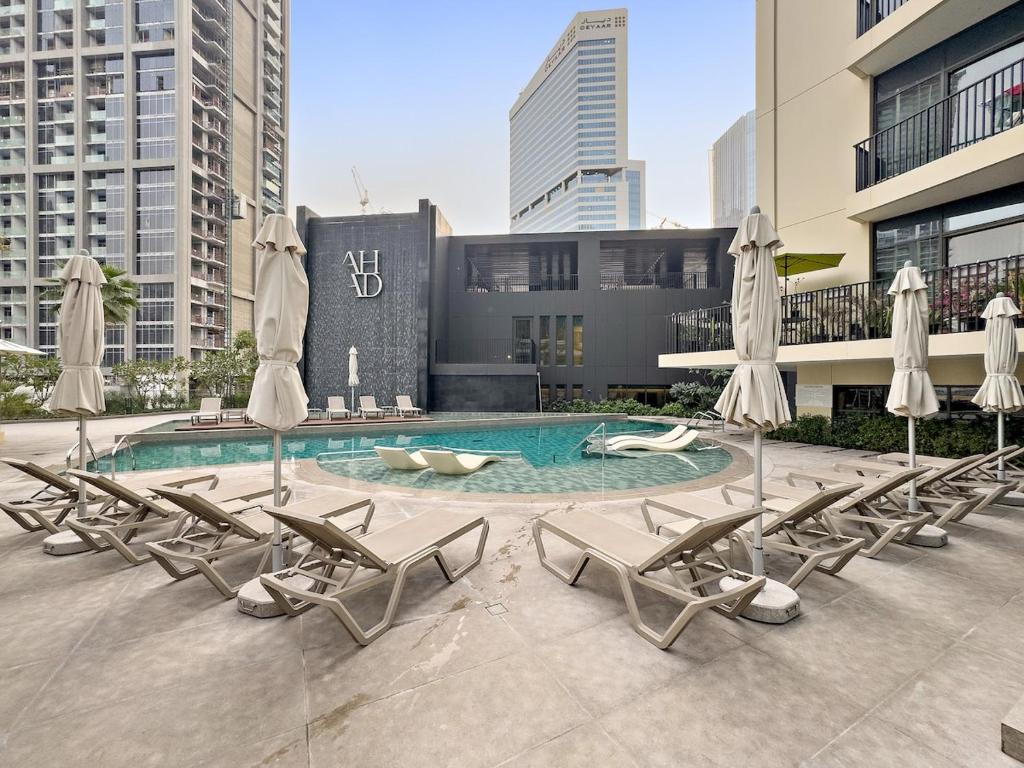 einen Pool mit Liegestühlen und Sonnenschirmen in der Unterkunft Business Bay Studio Near Dubai Mall, Burj Khalifa & Downtown Hotspots in Dubai