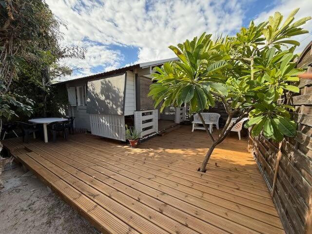 a wooden deck with a table and a tree at Bungalow Chalet du Lagon proche lagon La Saline in Saint-Paul