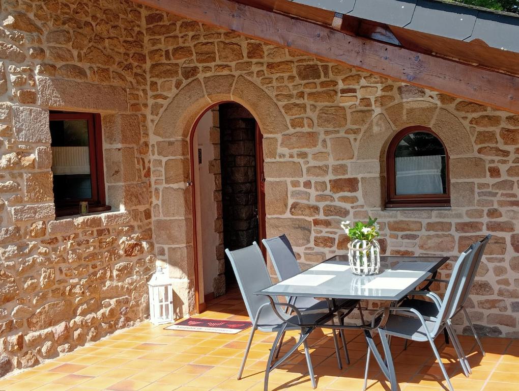 une table et des chaises devant un bâtiment en pierre dans l'établissement La Maison du Bonheur, à Mégrit