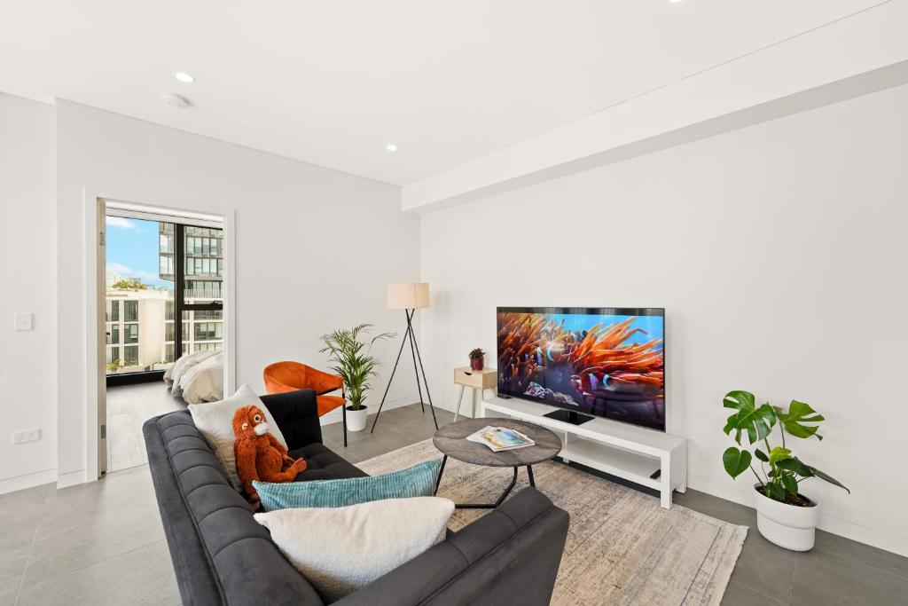 Una sala de estar con un sofá y un televisor. en Sydney Olympic Park Escape w Car Space Height 2m, en Sídney