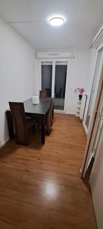 - une salle à manger avec une table et des chaises sur du parquet dans l'établissement chambre chez raissa, à Trappes