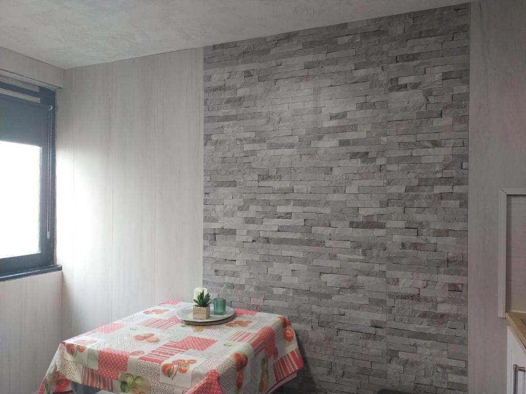 a room with a table and a brick wall at Le petit studio du Tourmalet pied des pistes - La Mongie in La Mongie