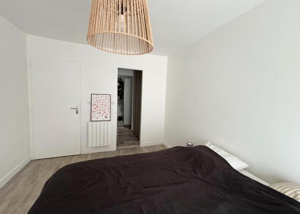 une chambre avec un lit et un lustre dans l'établissement Maison calme entre mer et marais, à Longeville-sur-Mer