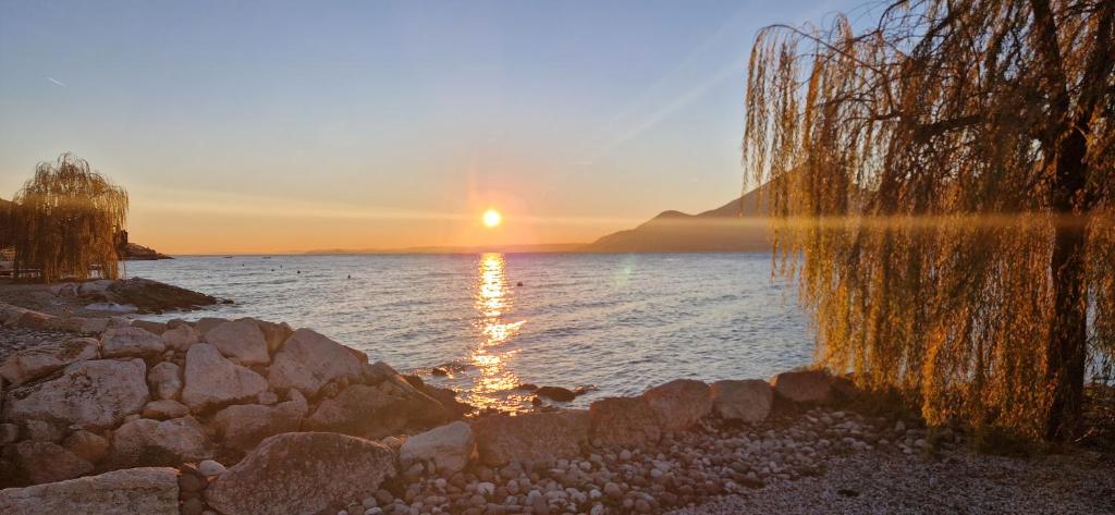 a sunset over a body of water with rocks at Casa Manu in Brenzone sul Garda