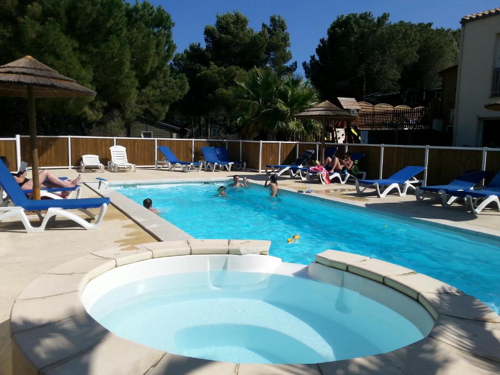 uma piscina com cadeiras e pessoas na água em Parc résidentiel les Hauts de Baldy em Agde
