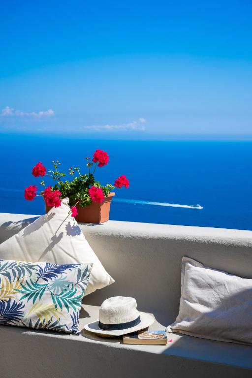 a seat with a hat and a flower pot on a balcony at Blue Moon House Praiano in Praiano