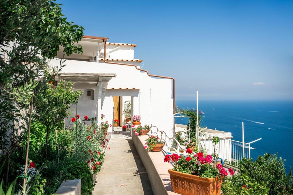 una casa blanca con flores en un balcón en Blue Moon House Praiano, en Praiano