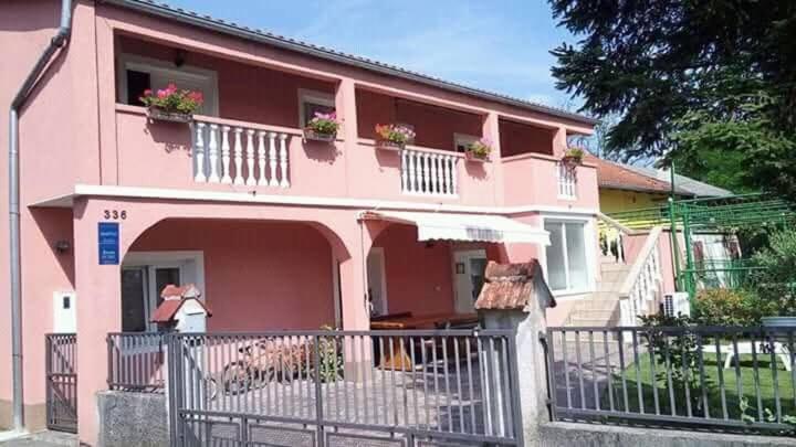 a pink house with a fence in front of it at Apartman Antonia in Podhum