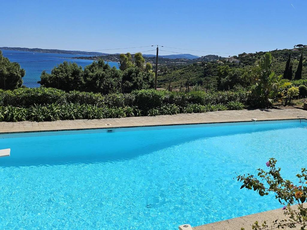 une grande piscine bleue avec vue sur l'eau dans l'établissement Villa de Maître pour 12 avec piscine privée aux Issambres - FR-1-768-111, à Sainte-Maxime