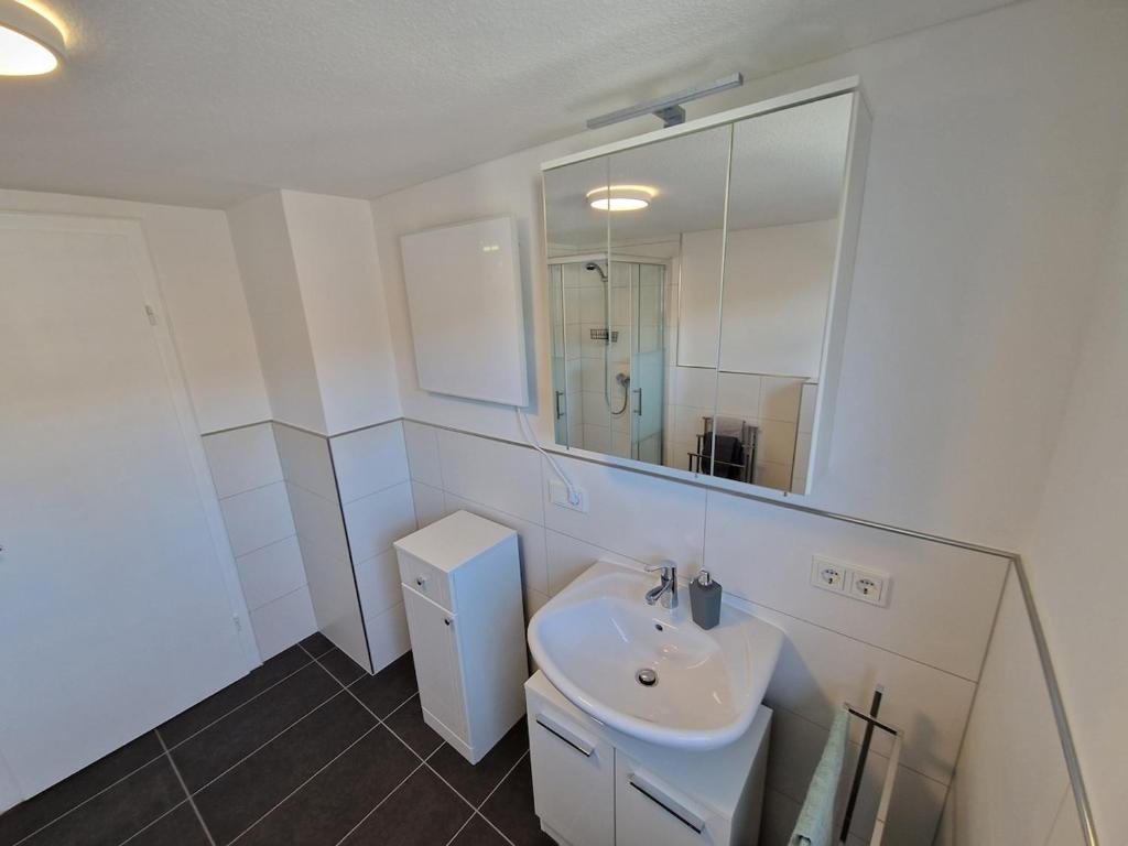 a white bathroom with a sink and a mirror at Ferienwohnung Wiese in Langelsheim
