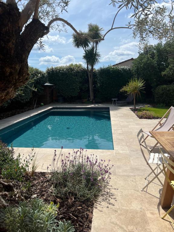 - une piscine dans un jardin avec une table et des chaises dans l'établissement Appartement de charme avec accès piscine, à Talence