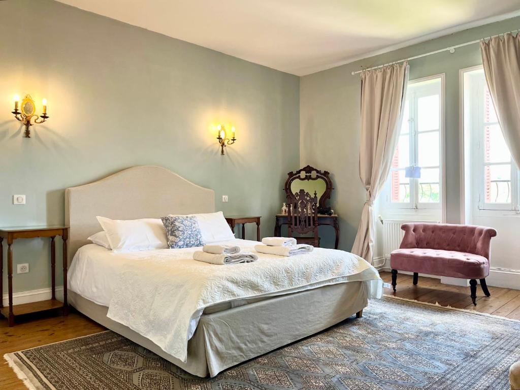 a bedroom with a large bed and a chair at La Source in Availles-Limouzine