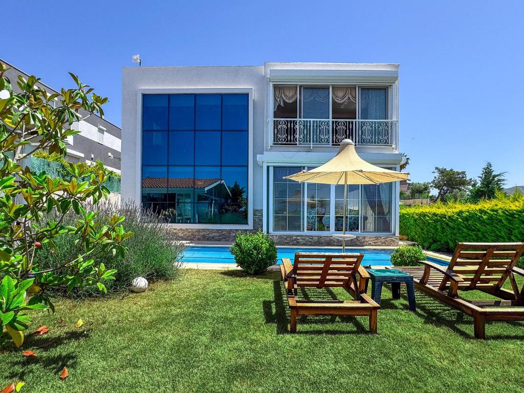 a house with two chairs and an umbrella in the yard at Villa Limon in Kuşadası