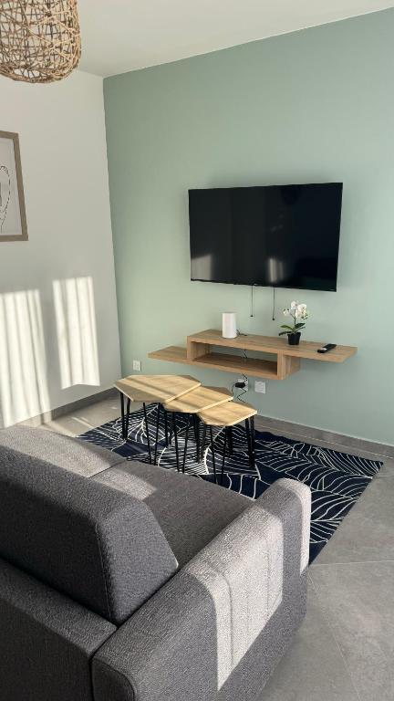 un salon avec un canapé, une table et une télévision dans l'établissement Le Détour - T2 de standing neuf, à Perpignan