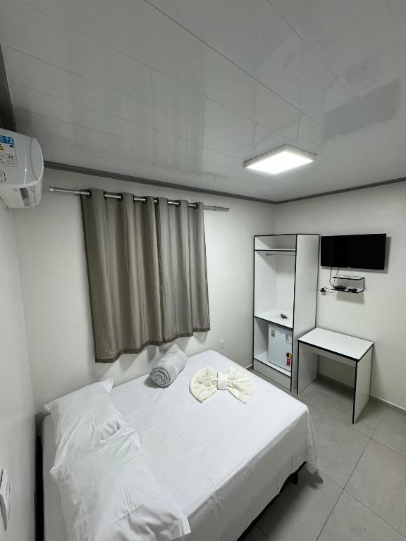 a bedroom with a white bed and a television at Hotel King Palace - Hotel Irituia in Irituia