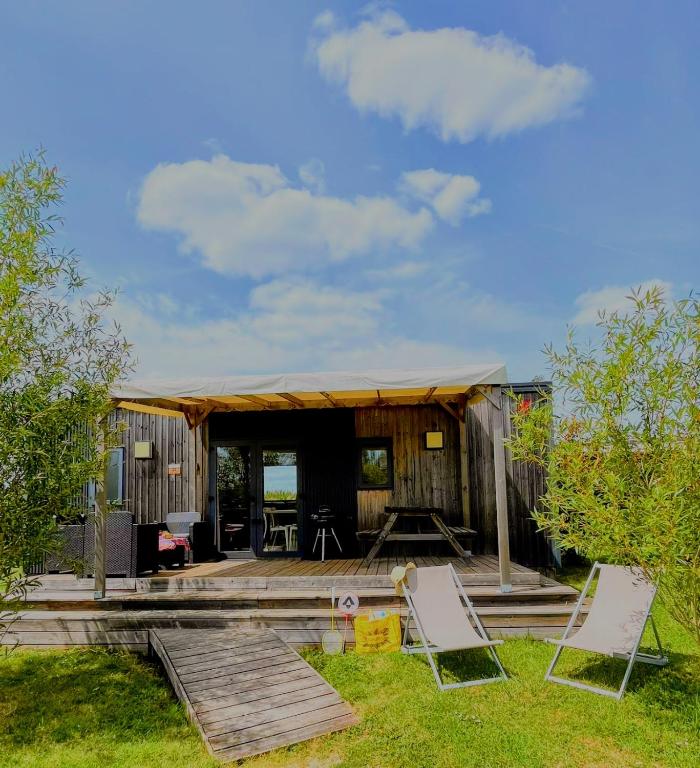 une maison avec deux chaises dans l'herbe dans l'établissement Camping Chambord, à Mont-près-Chambord