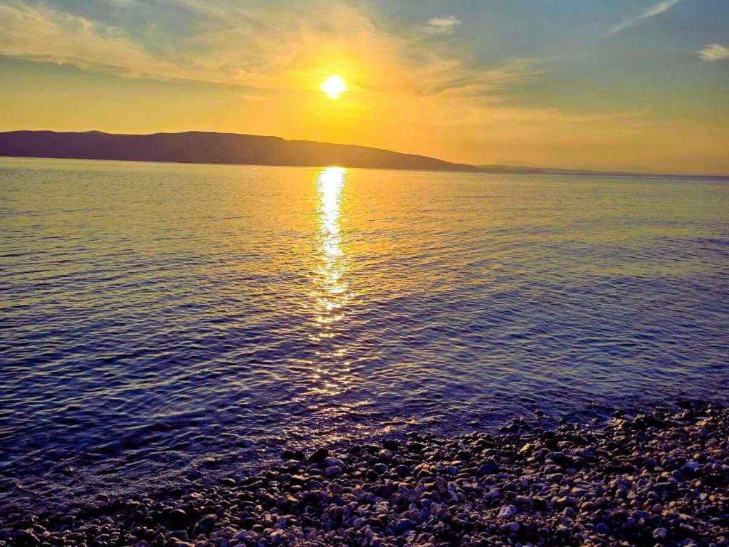 a sunset on the shore of a body of water at LOVELY APARTMENTS Senj - Spectacular Sea View & Free Parking & WI-FI in Senj