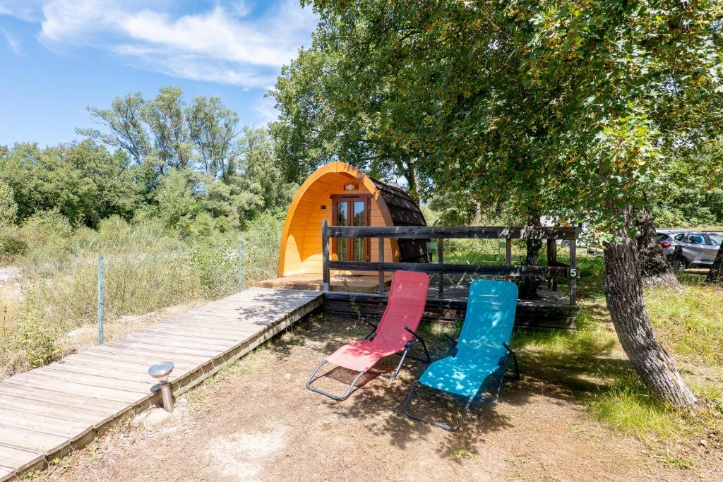 deux chaises assises devant une maison de jeu dans l'établissement Camping du Moulin de Thoard, à Thoard