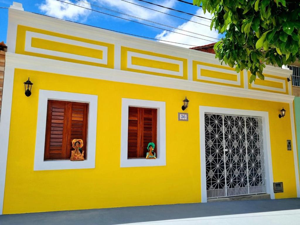 a yellow and white house with two windows at Casa Seu Quinca - Portalegre, RN Brasil in Portalegre