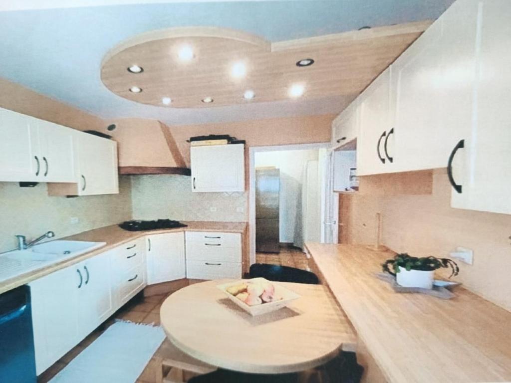 une cuisine avec des armoires blanches et une table en bois dans l'établissement Résidence Frontière Basel Airport, à Saint-Louis