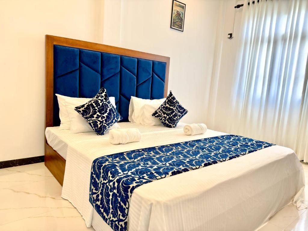 a bedroom with two beds with a blue headboard at Shelo Transit Hotel in Katunayaka
