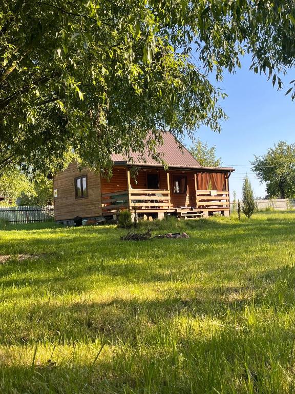 a log cabin in a field of green grass at Chatka nad Stawami in Bierdzież