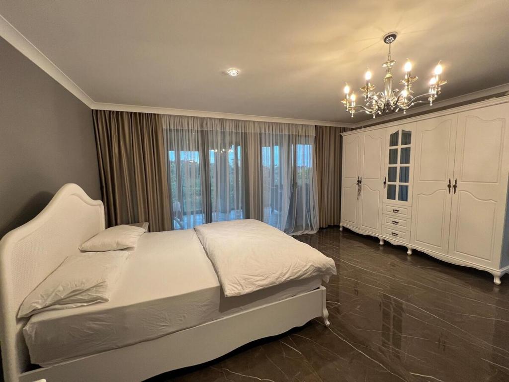 a bedroom with a white bed and a chandelier at Trabzon House - Pool, Sea View & Nature in Bostancı