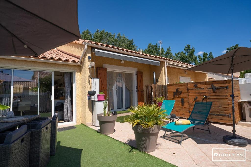 un patio avec deux chaises et un parasol dans l'établissement Vias-plage - Villa climatisée de 65m2 à 600m de la plage, à Vias