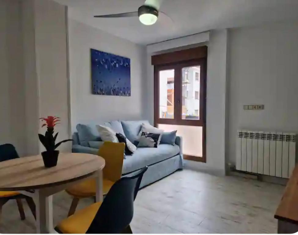 un soggiorno con un divano blu e un tavolo di Apartamento Gascona a Oviedo