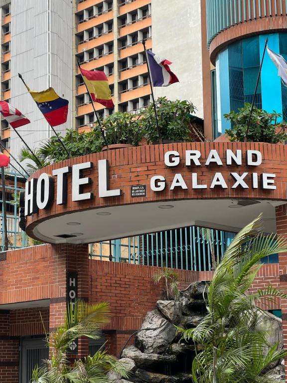 a hotel sign in front of a building with flags at Hotel Grand Galaxie in Caracas