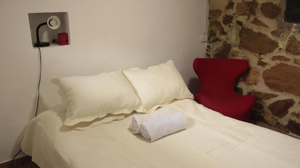 1 dormitorio con cama blanca y silla roja en La Posada de Juancho, en Junín
