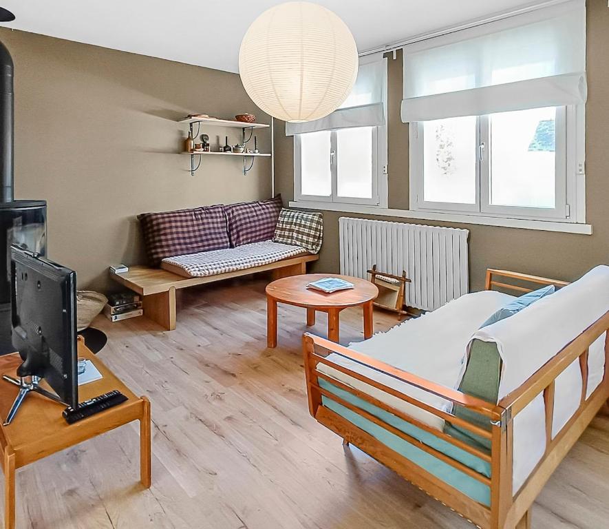 a room with a bed and a tv and a couch at Maison plages & centre à pieds - proche GR34 in Saint-Pol-de-Léon