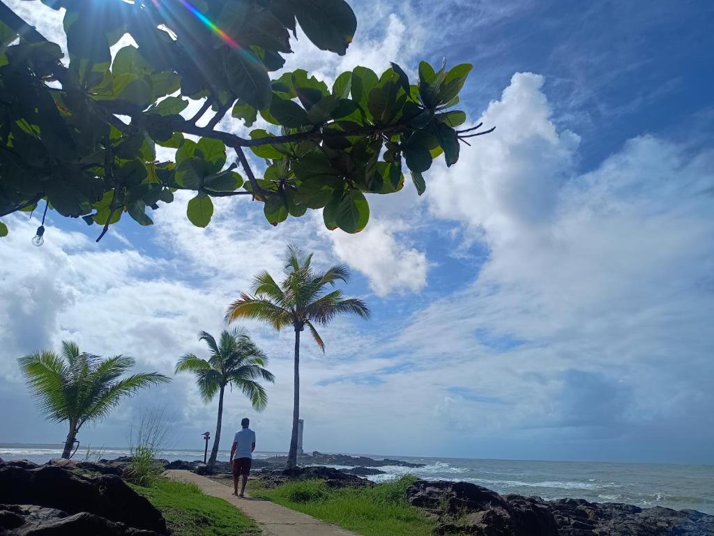 a man standing on the beach with palm trees at Apartamento Próximo a Pituba in Itacaré