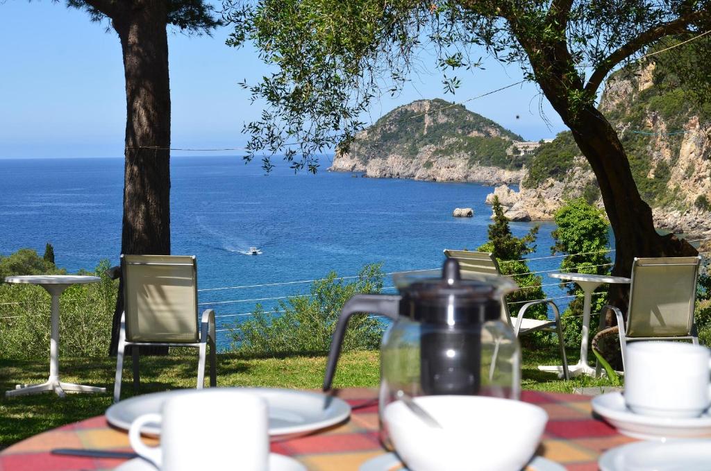 a table with a tea pot on it with a view of the ocean at Anna Pension in Liapades