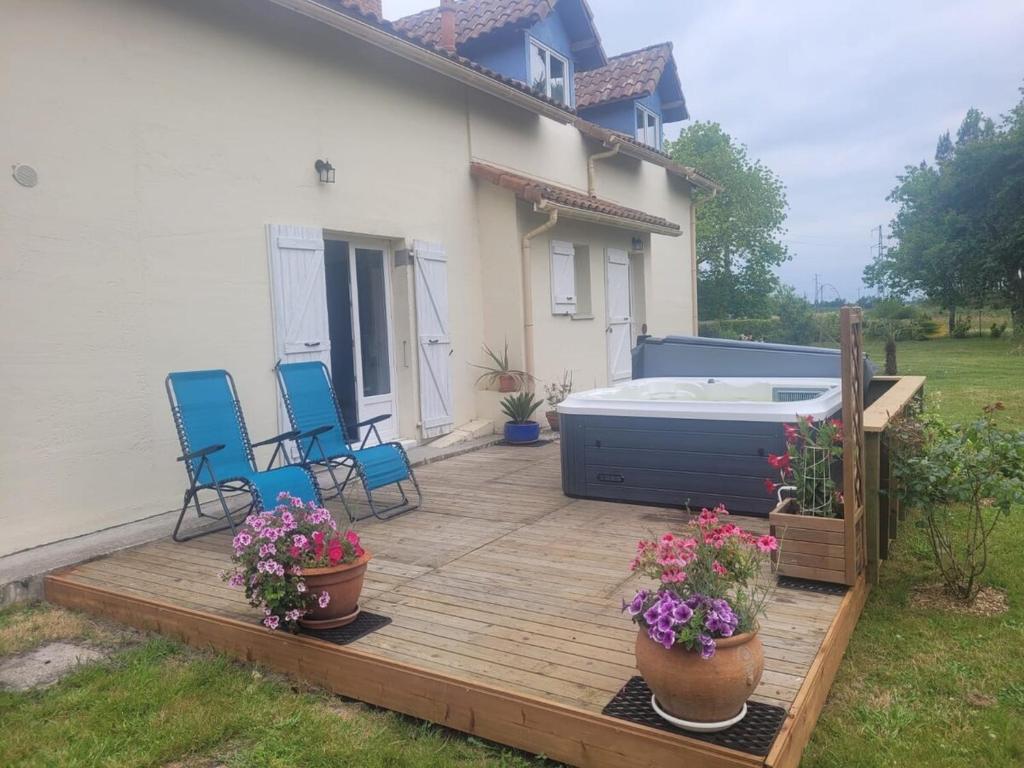 a wooden deck with chairs and a hot tub at Maison spacieuse au calme in Morcenx