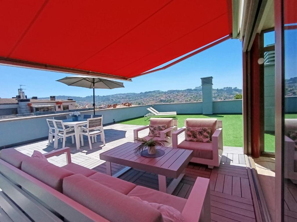 a patio with a couch and a table and an umbrella at Ático Chill-Out de lujo con piscina y garaje gratis in Vigo