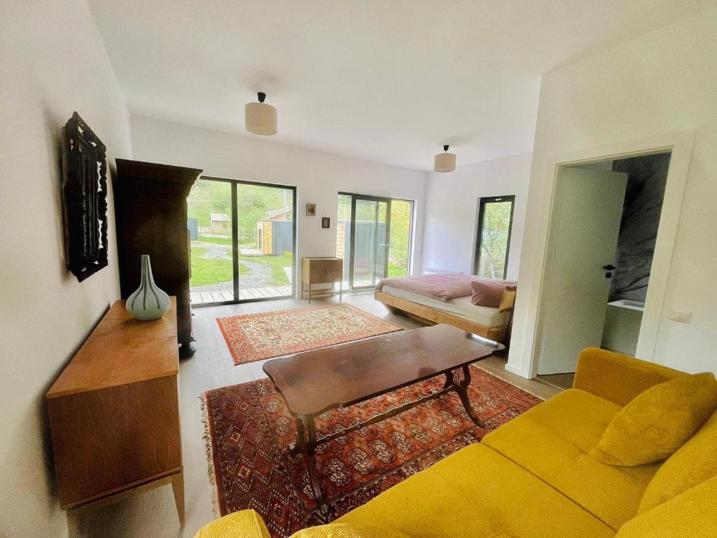 a living room with a yellow couch and a bed at Rai Village in Băniţa