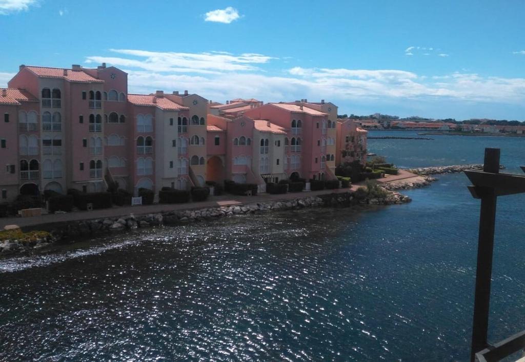 un groupe de bâtiments à côté d'une masse d'eau dans l'établissement Beau appartement face à l eau, au Barcarès