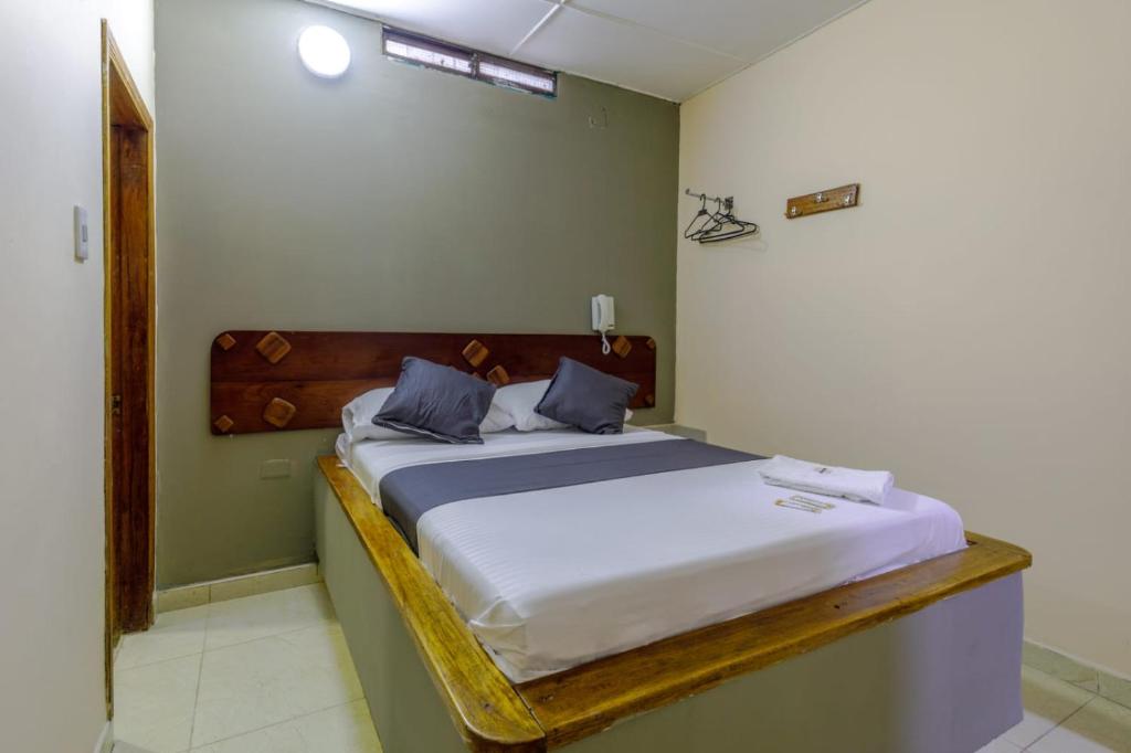 ein Schlafzimmer mit einem großen Bett mit einem hölzernen Kopfteil in der Unterkunft Hotel Don Fermín in Barranquilla