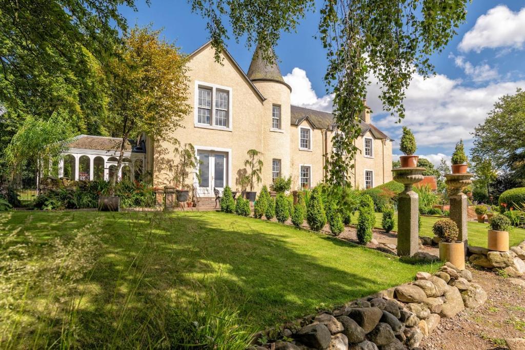 an exterior view of a large house with a yard at Luxury 5-Bed Country Retreat in the Angus Glens in Glenogil