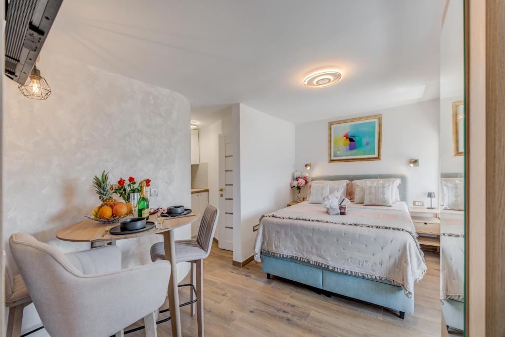 a bedroom with a bed and a table and a kitchen at Seafront Apartment Balcony Panoramic View in Kaštela