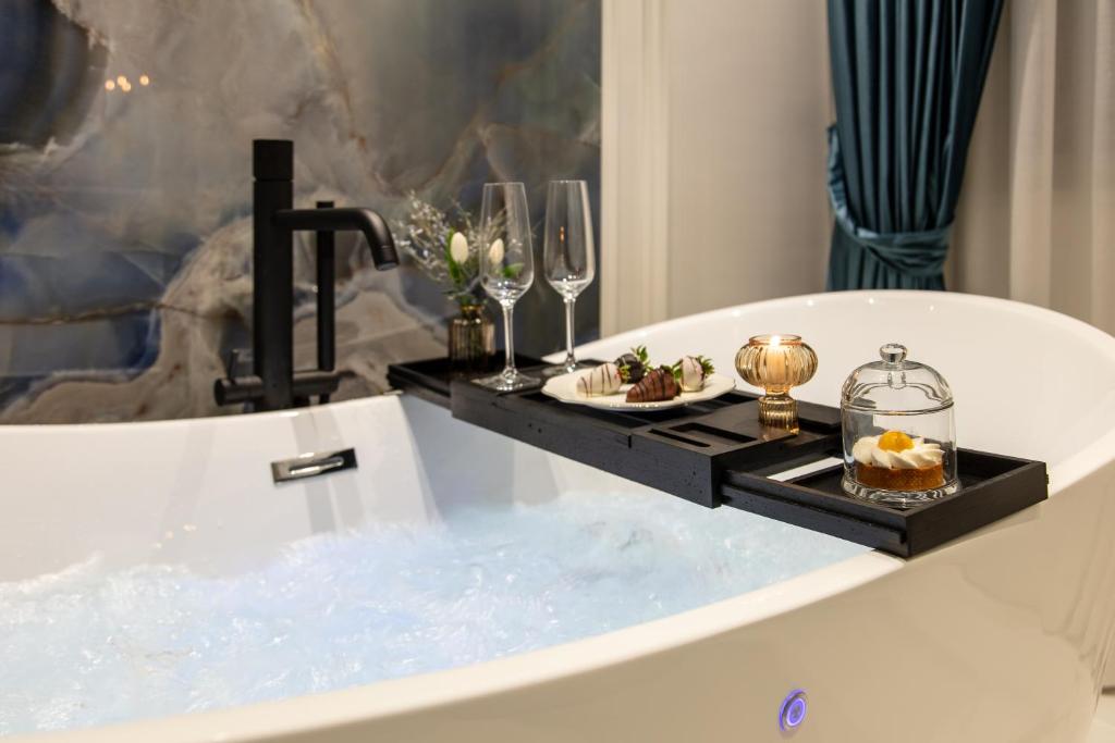 a bathtub with a tray of food and wine glasses at Dama Luxury Suites Pompei in Pompei