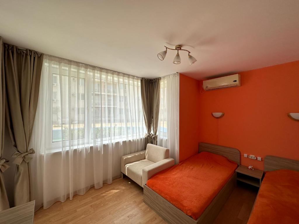 a bedroom with orange walls and a bed and a chair at The Sunny Spot in Sunny Beach