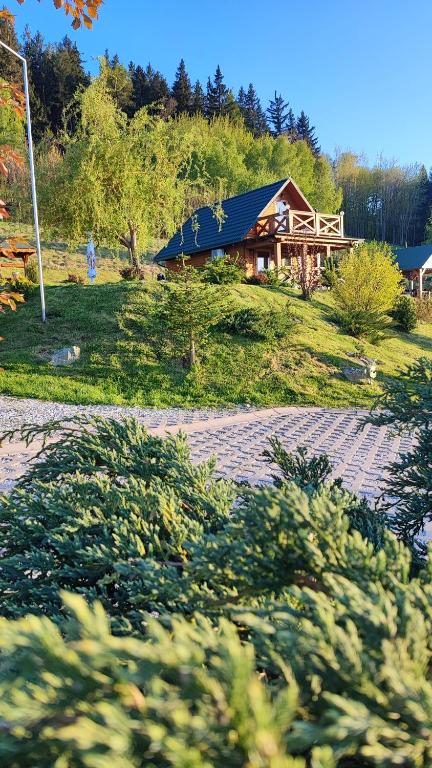 a house on a hill with a building in the background at DOMKI KOLOROWE in Marciszów