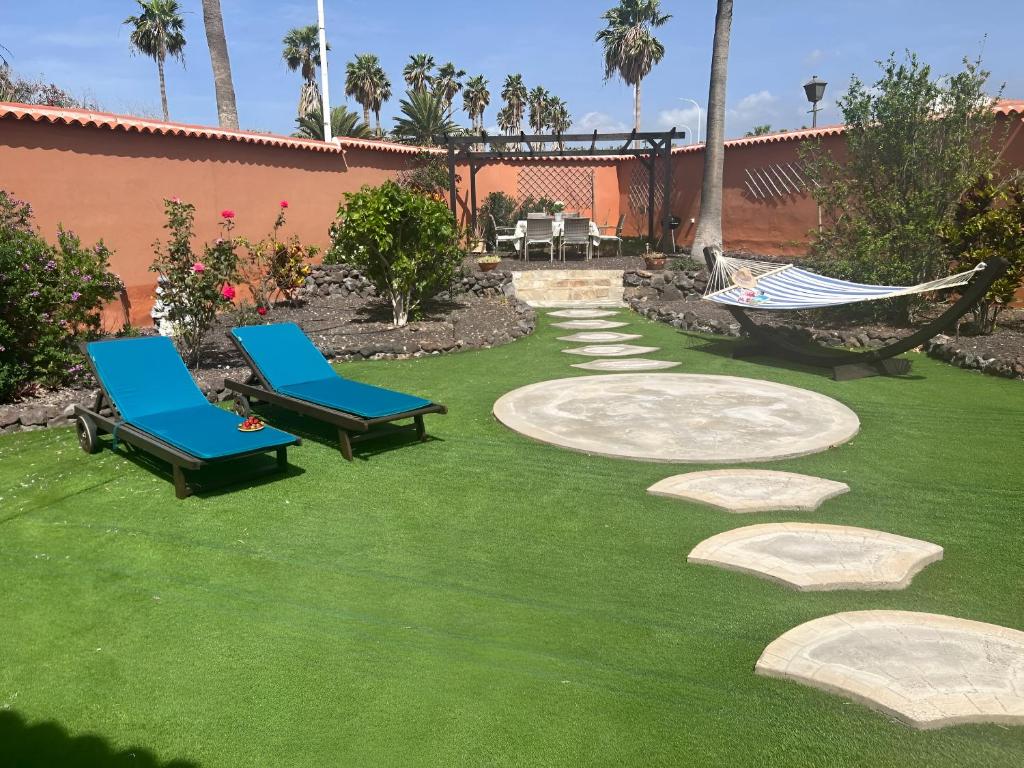 a yard with two chairs and a hammock on the grass at Villa Chloé in San Miguel de Abona