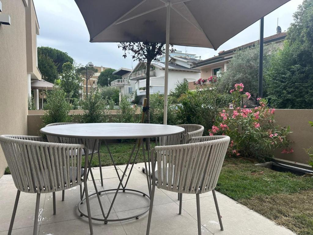 a table and chairs with an umbrella on a patio at Appartamento Toscanini in Milano Marittima