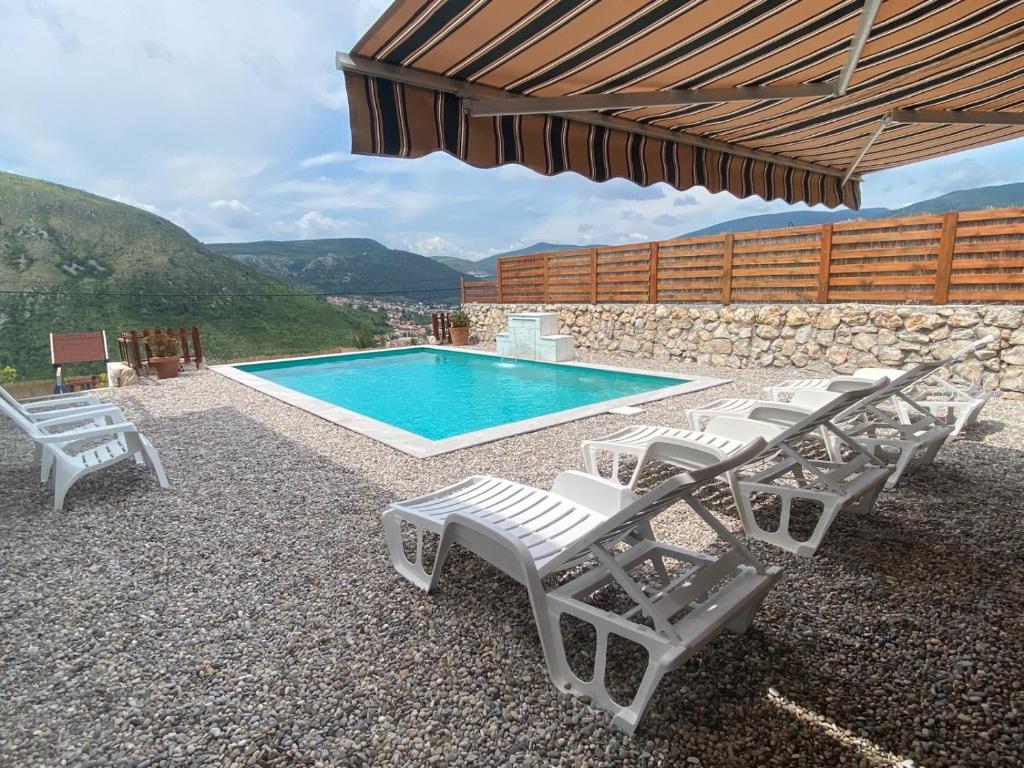 a swimming pool with white lounge chairs and a table and a swimming pool at House on the hill in Mostar