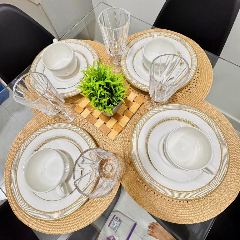 a table with plates and glasses and a plant on it at Apartamento aconchegante completo -Próximo ao Aeroporto-COP30 in Belém