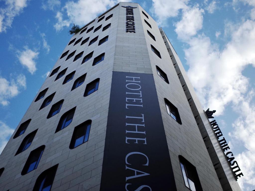 a tall white building with a sign on it at Hotel the Castle Jamsil Sports Complex in Seoul