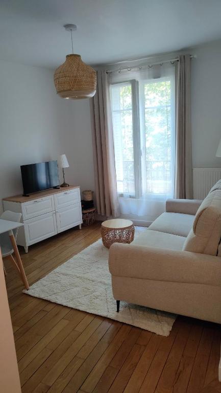 un salon avec un canapé et une télévision dans l'établissement Boul'Bohème - 4 guests 1 bedroom 2 beds 1 bathroom, à Boulogne-Billancourt